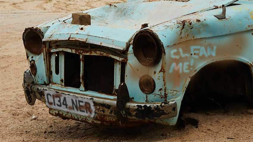 A rusty old car with the registration C134NER (or Cleaner)