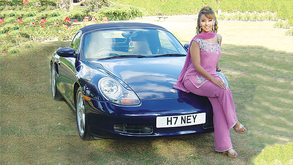 Honey Kalaria sitting on a Porsche with the number plate H7 NEY on it