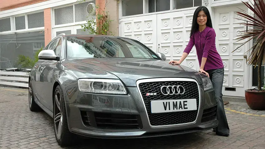 Vanessa-Mae standing next to a car bearing registration V1 MAE